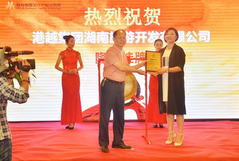湖南省委宣传部副部长杨金鸢(左一)在挂牌仪式上为港越集团湖南旅游开发有限公司周香香女士颁发挂牌上市牌匾。.JPG