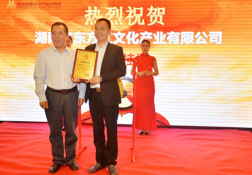 湖南省文化厅副厅长肖凌之（左一）在挂牌仪式上为湖南省东方红文化产业有限公司文锋颁发挂牌上市牌匾。.JPG